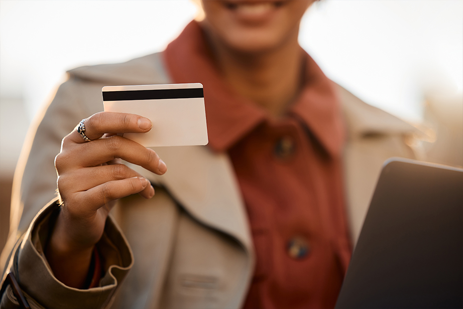 5 Benefícios e 5 Malefícios do Uso do Cartão de Crédito 18 Closeup de mulher segurando cartão de crédito e laptop.